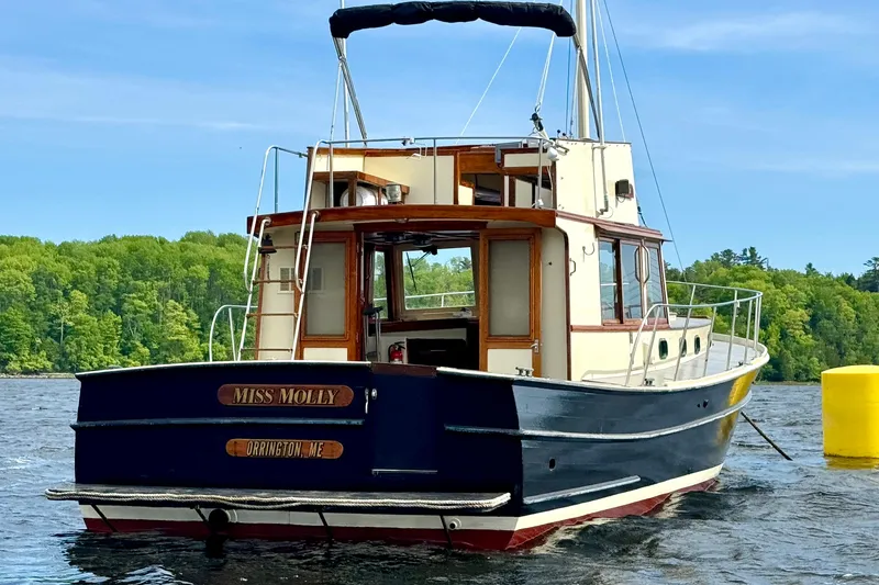 Slide: The Image of 1976 Downeast Flybridge Cruiser on water, named "Miss Molly," with lush green shoreline background. - 5