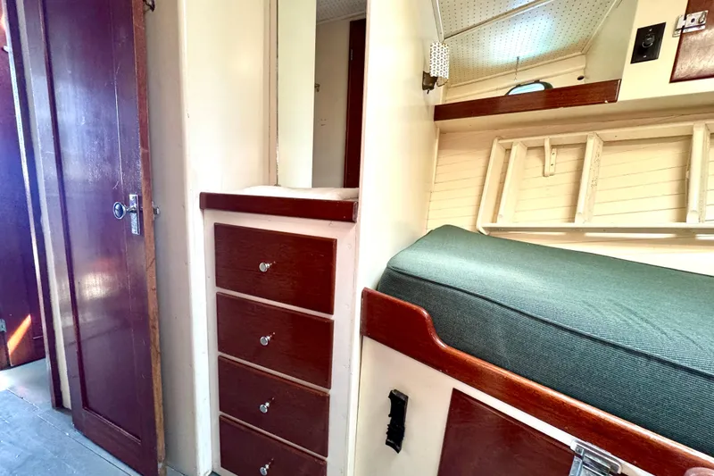 Slide: The Image of 1976 Downeast Flybridge Cruiser cabin interior with wooden drawers and green cushioned seating. - 50