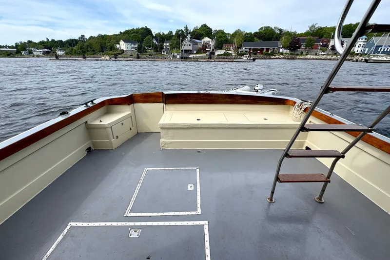 Slide: The Image of 1976 Downeast Flybridge Cruiser deck with seating, ladder, and scenic waterfront view. - 52