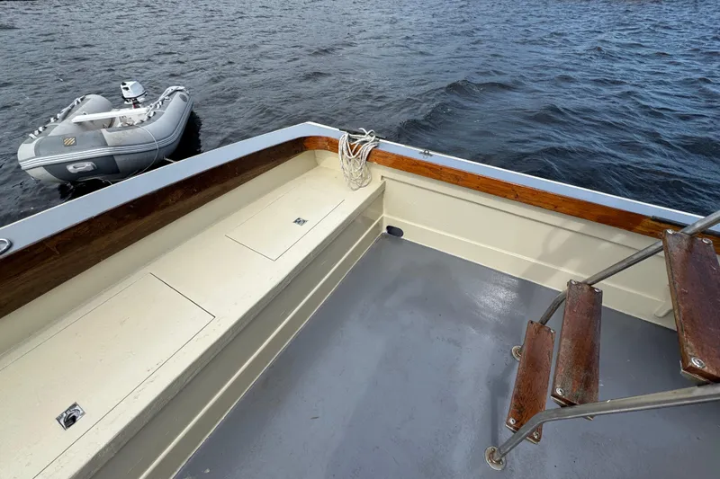 Slide: The Image of 1976 Downeast Flybridge Cruiser deck with wooden accents and nearby inflatable boat. - 56