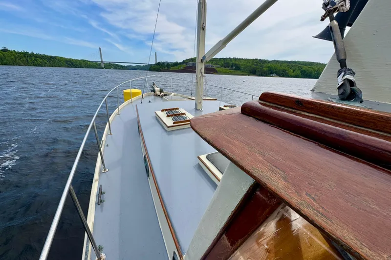 Slide: The Image of 1976 Downeast Flybridge Cruiser on a scenic river with a bridge in the background. - 59