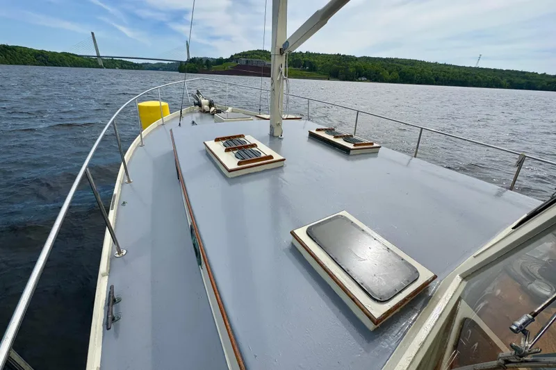 Slide: The Image of 1976 Downeast Flybridge Cruiser on water, showcasing deck and scenic bridge view. - 60