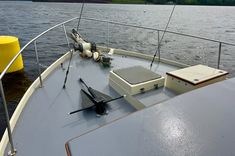 Slide: The Image of 1976 Downeast Flybridge Cruiser deck with anchor and winch on calm water. - 61