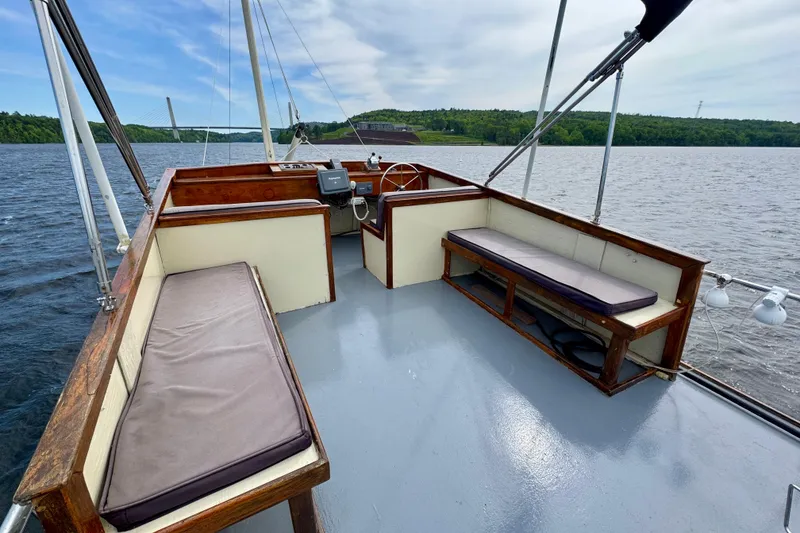 Slide: The Image of 1976 Downeast Flybridge Cruiser with spacious deck, wooden seating, and scenic river view. - 69