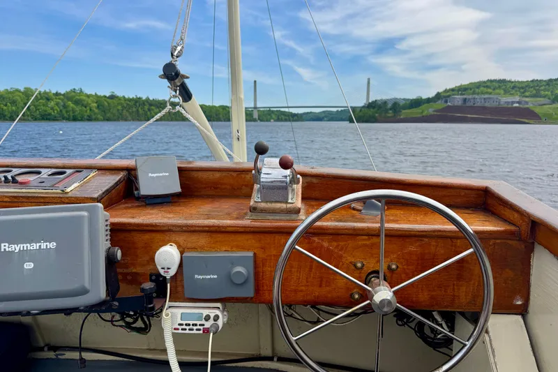 Slide: The Image of 1976 Downeast Flybridge Cruiser helm with Raymarine equipment, overlooking scenic river and bridge. - 72