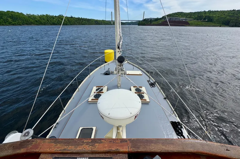 Slide: The Image of 1976 Downeast Flybridge Cruiser on scenic waterway, lush greenery, and distant bridge. - 73