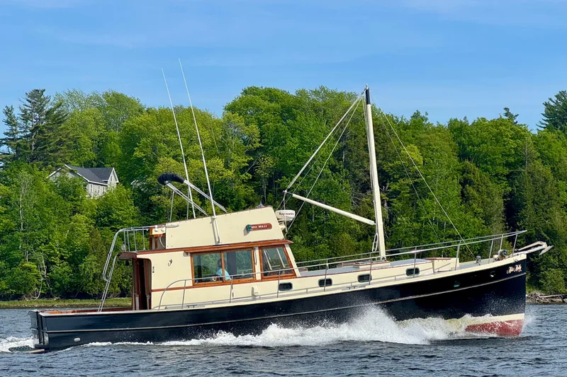 Slide: The Image of 1976 Downeast Flybridge Cruiser sailing on a scenic lake with lush green forest backdrop. - 76