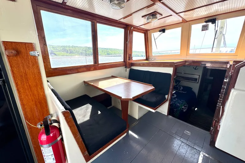 Slide: The Image of Interior of a 1976 Downeast Flybridge Cruiser with wooden dining area and scenic windows. - 8