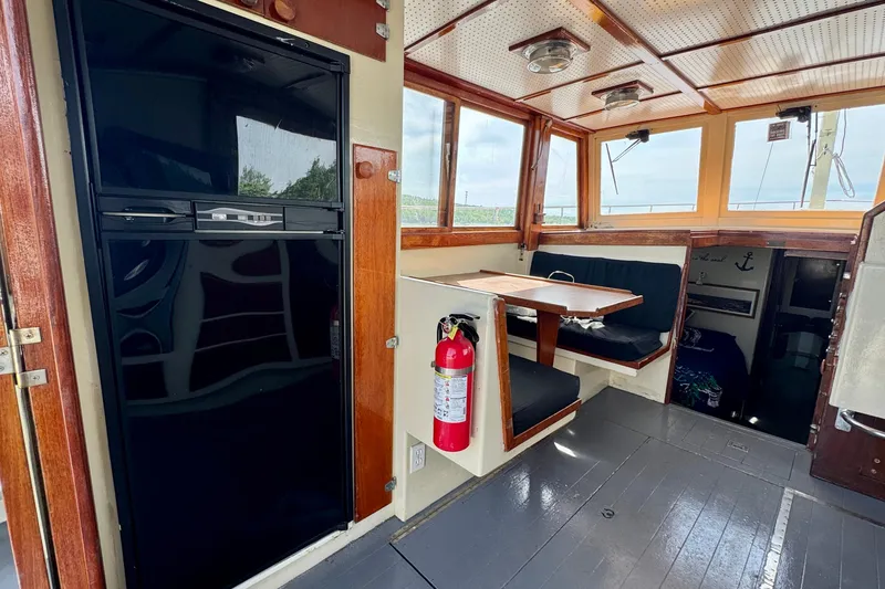 Slide: The Image of 1976 Downeast Flybridge Cruiser interior with dining area, fridge, and wooden accents. - 9