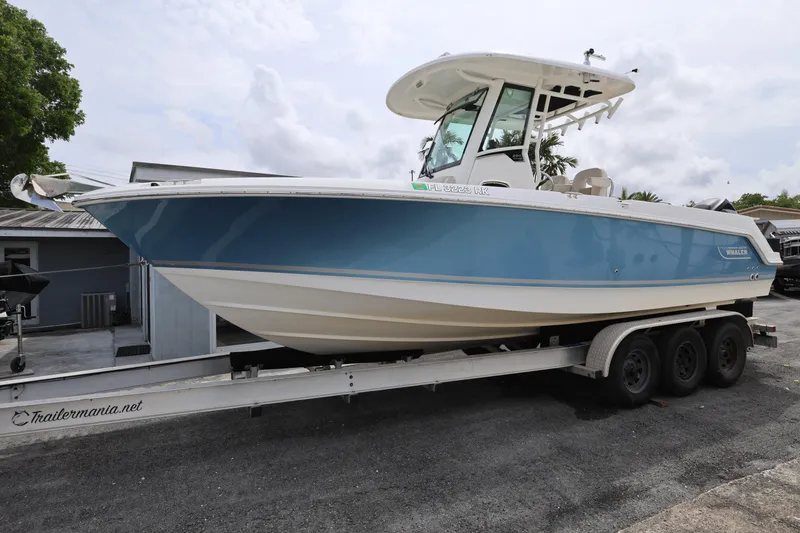 The Image of 2016 Boston Whaler 250 Outrage boat on trailer, blue and white design, parked outdoors. - 0