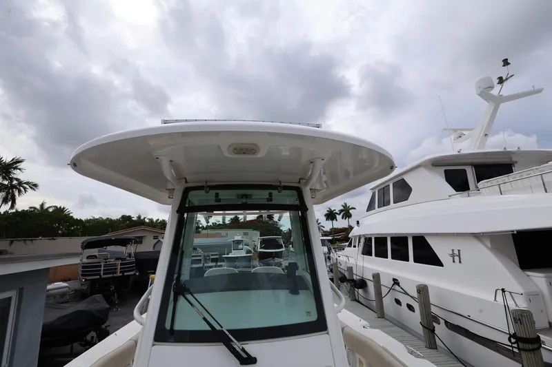 Slide: The Image of 2016 Boston Whaler 250 Outrage boat docked beside larger yachts under cloudy sky. - 18