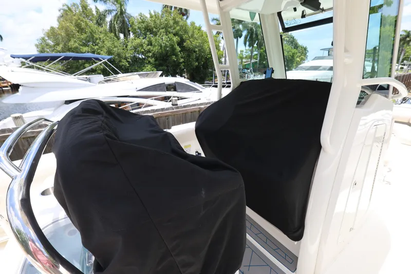 Slide: The Image of 2016 Boston Whaler 250 Outrage boat interior with covered seats, docked near other boats. - 27