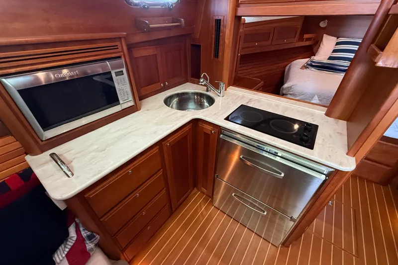 Slide: The Image of 2017 Sabre 38 Salon Express galley with microwave, sink, stovetop, and wood cabinetry. - 60