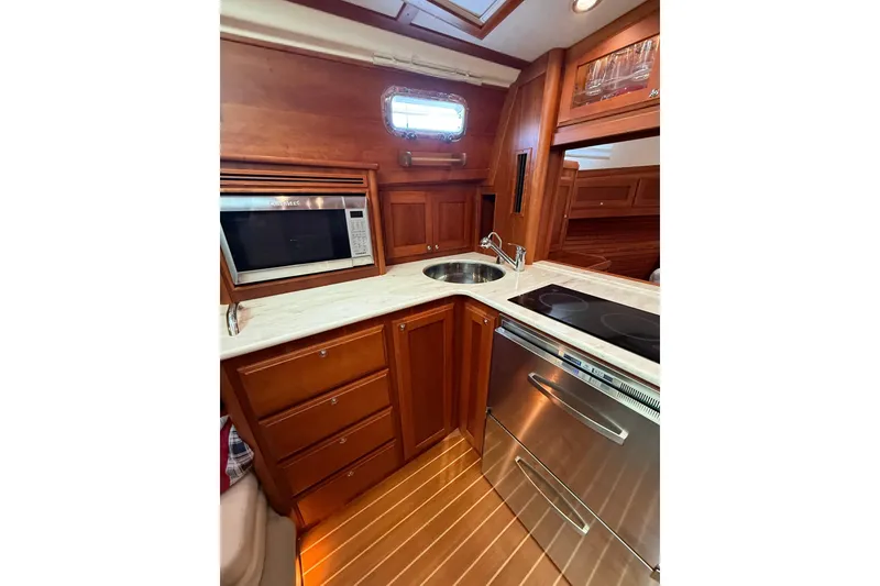 Slide: The Image of 2017 Sabre 38 Salon Express galley with microwave, sink, and stove in wooden interior. - 62