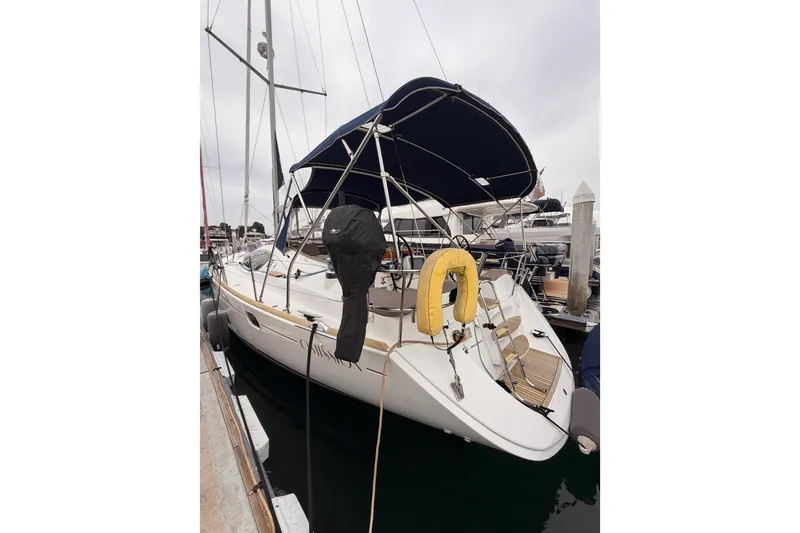 Slide: The Image of 2014 Jeanneau Sun Odyssey 50 DS sailboat docked, featuring a blue canopy and yellow life preserver. - 10