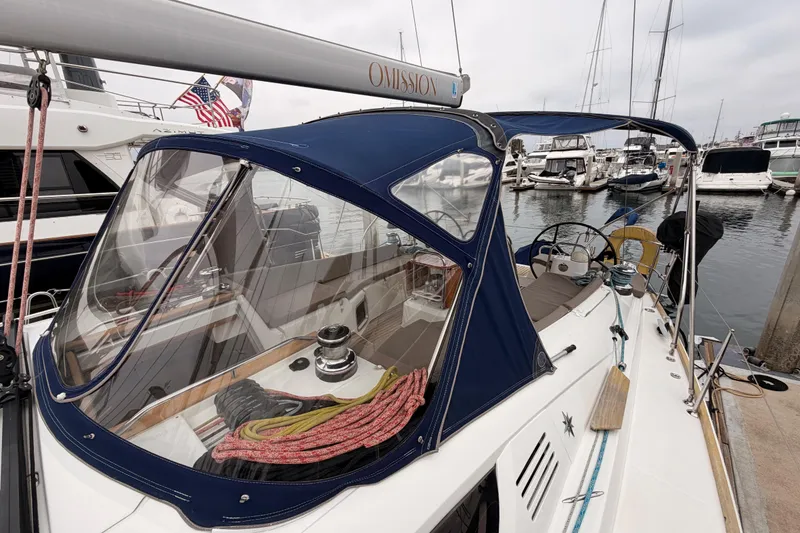Slide: The Image of 2014 Jeanneau Sun Odyssey 50 DS sailboat docked at marina, featuring blue canopy and American flag. - 23