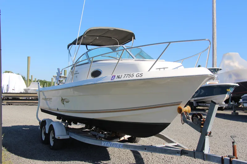 Slide: The Image of 2003 Aquasport 215 Explorer boat on trailer, parked outdoors under clear blue sky. - 12