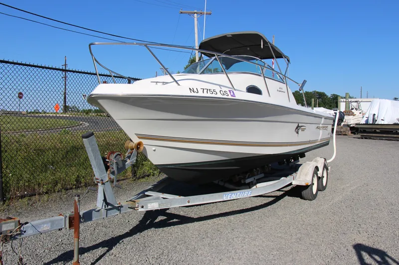 Slide: The Image of 2003 Aquasport 215 Explorer boat on trailer, parked outdoors on gravel. - 3