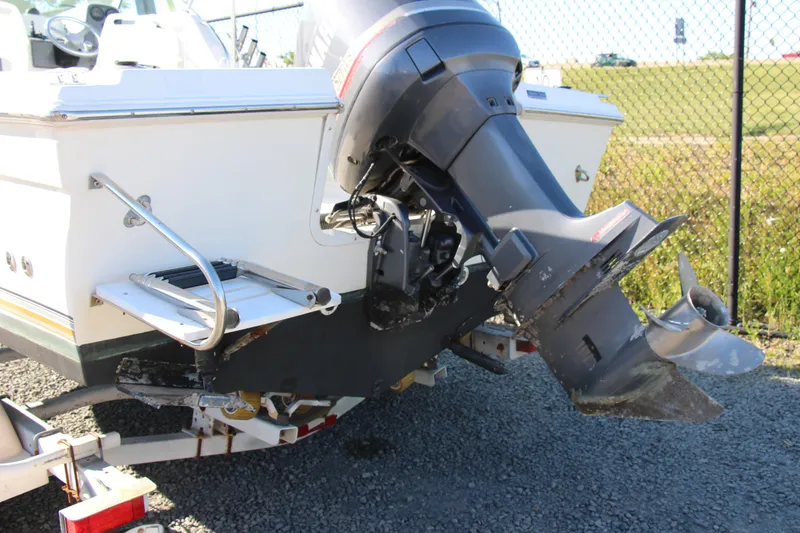 Slide: The Image of 2003 Aquasport 215 Explorer boat with outboard motor and ladder, parked on a trailer. - 9