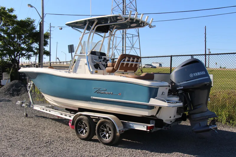 Slide: The Image of 2022 Pioneer 222 Islander boat with Yamaha engine on trailer, parked outdoors. - 2