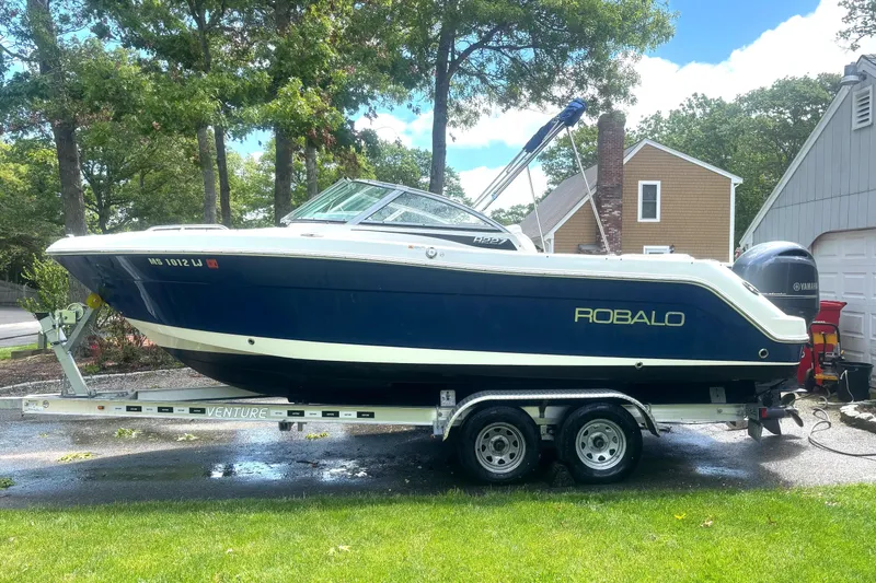 The Image of 2016 Robalo R227 Dual Console boat on trailer, parked in residential driveway. - 0