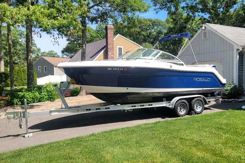 Slide: The Image of 2016 Robalo R227 Dual Console boat on trailer, parked in residential driveway. - 1