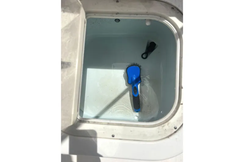 Slide: The Image of Open storage compartment on 2016 Robalo R227 Dual Console with cleaning brush inside. - 17