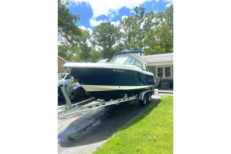 Slide: The Image of 2016 Robalo R227 Dual Console boat on trailer in driveway, surrounded by trees. - 19