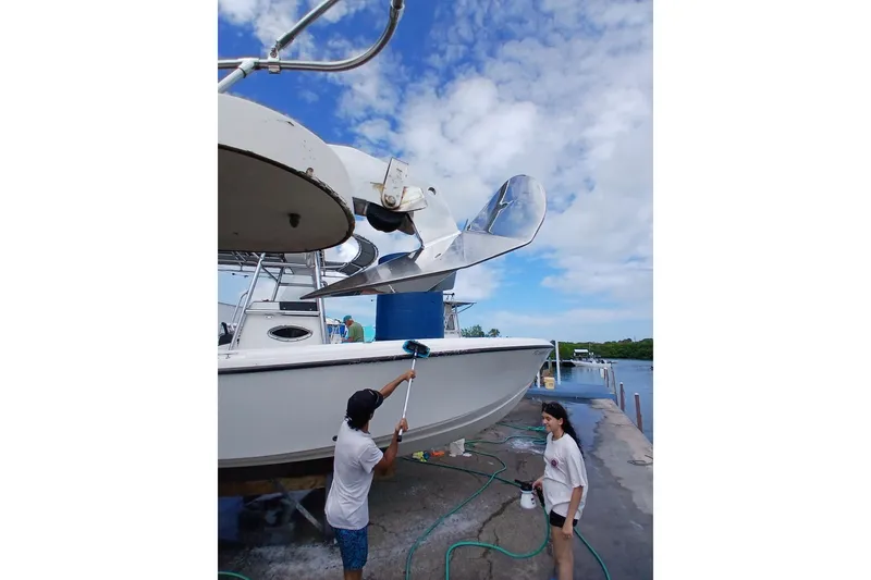 Slide: The Image of Two people cleaning a 1996 Grady-White Advance 247 boat at a dock. - 22