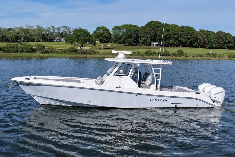 The Image of 2022 Everglades 365 Center Console boat cruising on a scenic lake. - 0