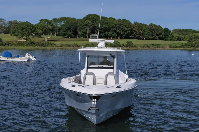 Slide: The Image of 2022 Everglades 365 Center Console boat on a serene lake with lush green backdrop. - 11
