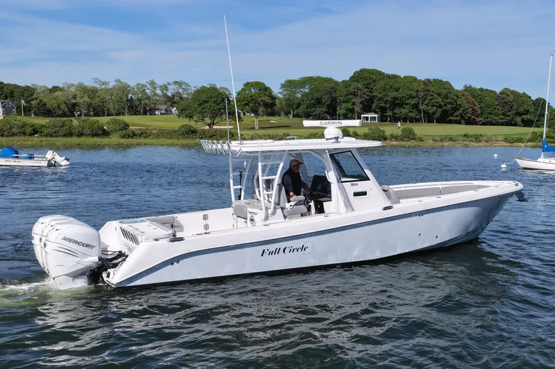 Slide: The Image of 2022 Everglades 365 Center Console boat cruising on a scenic lake with lush greenery. - 7