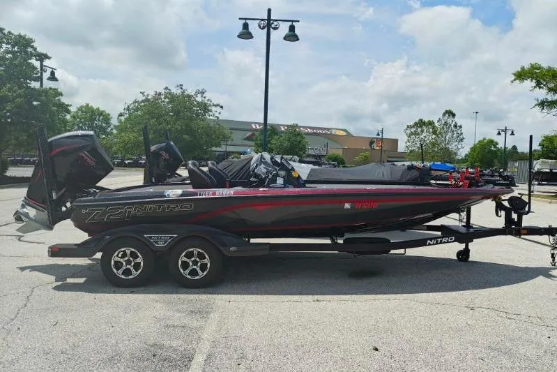 The Image of 2022 Nitro Z21 XL Pro boat on trailer in parking lot, under cloudy sky. - 1