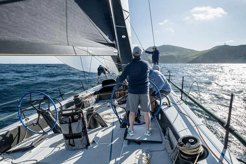 Slide: The Image of Sailors navigating Botin 56 yacht on open sea, 2018 model, under clear skies. - 2
