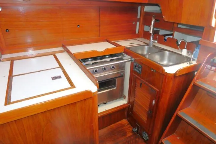 Slide: The Image of 1978 Tartan 37 yacht interior kitchen with wooden cabinetry, stove, and dual sink. - 16