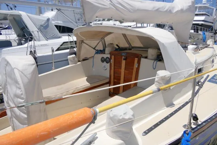 Slide: The Image of 1978 Tartan 37 sailboat docked at marina, featuring covered cockpit and wooden hatch. - 26