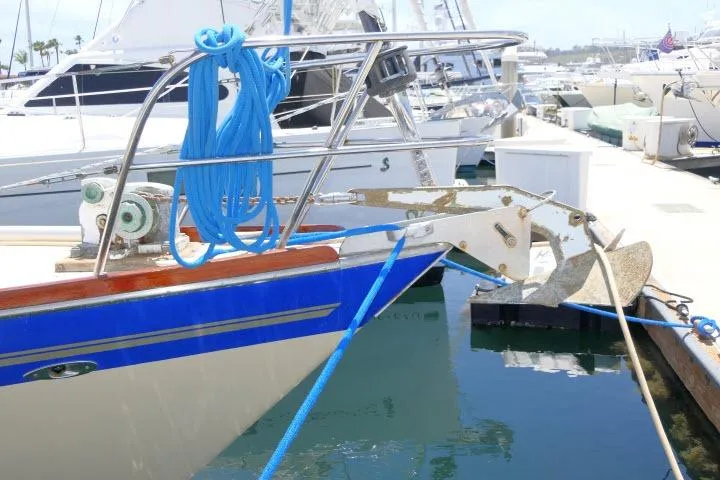 Slide: The Image of 1978 Tartan 37 sailboat docked, featuring blue trim and anchor at marina. - 48