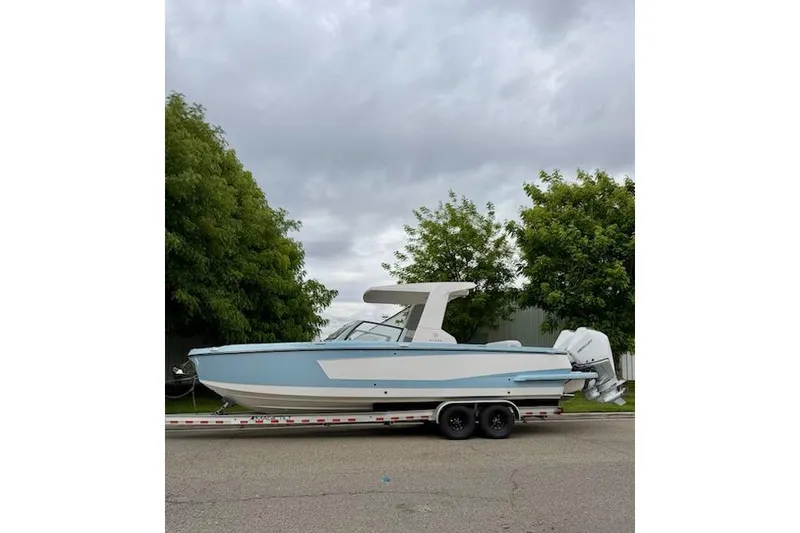 Slide: The Image of 2024 Aviara AV28 OB boat on trailer, parked outdoors with trees in background. - 1