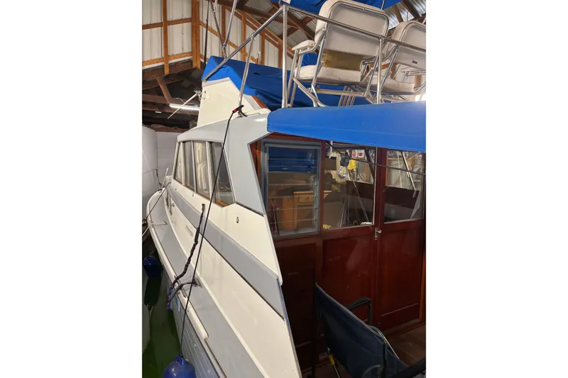 Slide: The Image of 1964 Pacemaker Flybridge Cruise boat with blue canopy and wooden interior in a boathouse. - 3