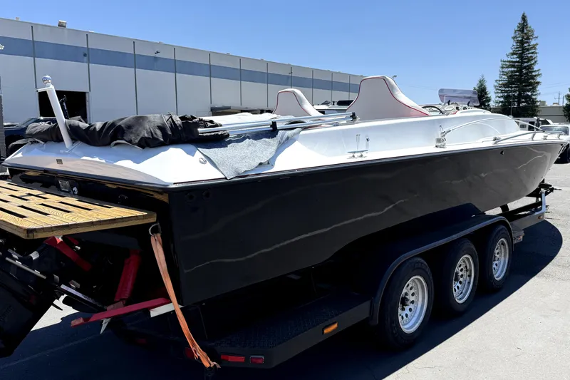 Slide: The Image of 1979 Charger 30 Cuddy boat on trailer, black hull, white interior, parked outdoors. - 5