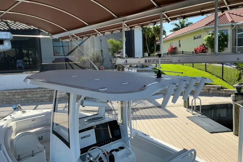 Slide: The Image of 2019 Sea Hunt Ultra 255 SE boat docked under a canopy with modern controls. - 18