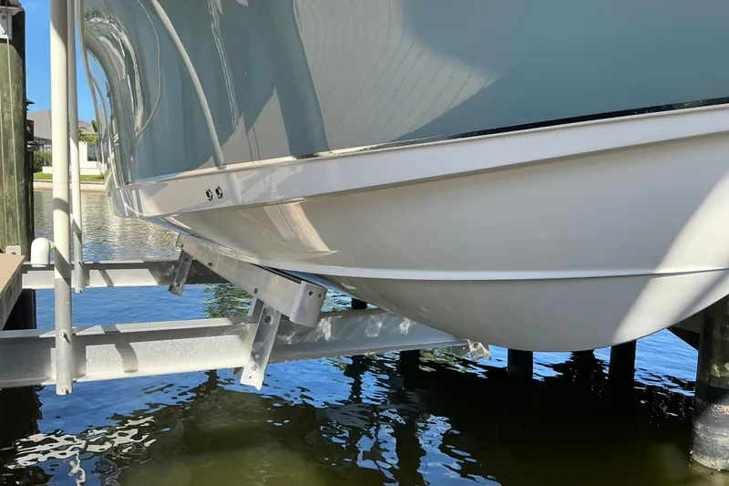 Slide: The Image of 2019 Sea Hunt Ultra 255 SE boat on lift, reflecting sunlight over water. - 2