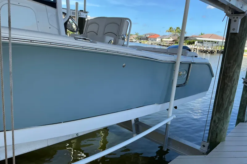 Slide: The Image of 2019 Sea Hunt Ultra 255 SE boat docked on a lift by the water. - 4