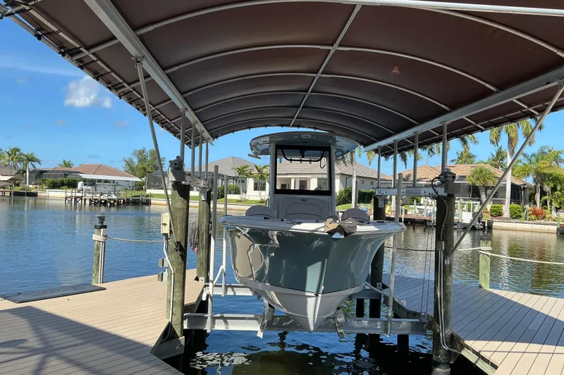 Slide: The Image of 2019 Sea Hunt Ultra 255 SE boat docked under canopy in a scenic waterfront setting. - 5