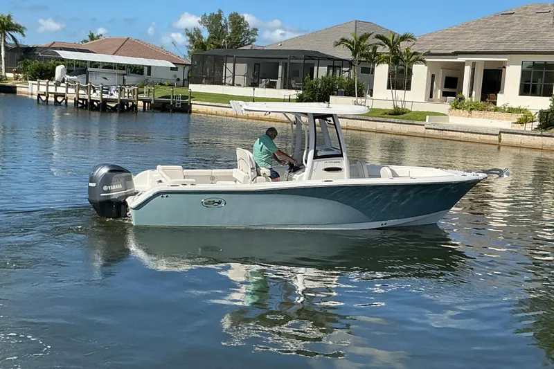 Slide: The Image of 2019 Sea Hunt Ultra 255 SE boat cruising on a calm residential waterway. - 50
