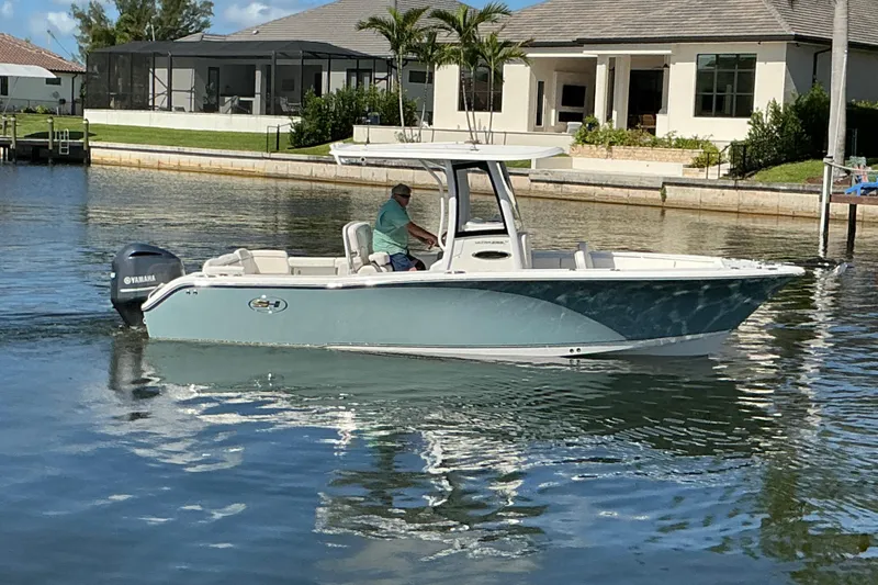Slide: The Image of 2019 Sea Hunt Ultra 255 SE boat cruising on a calm residential waterway. - 51