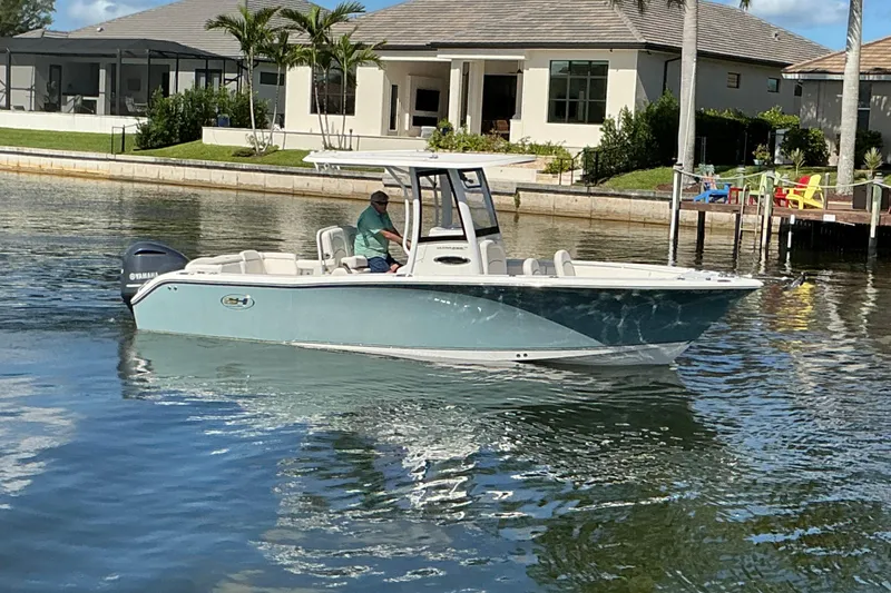 Slide: The Image of 2019 Sea Hunt Ultra 255 SE boat cruising on a sunny waterfront near modern homes. - 52