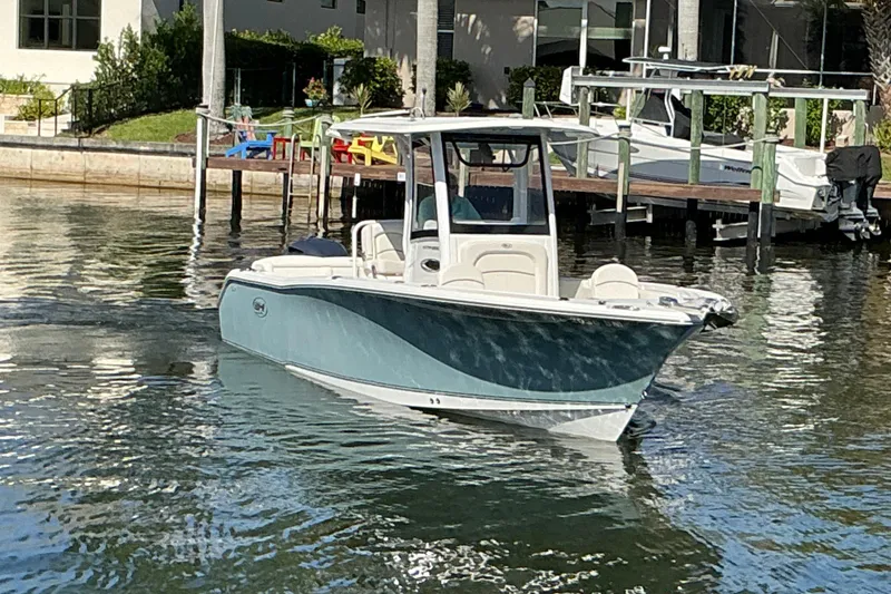 Slide: The Image of 2019 Sea Hunt Ultra 255 SE boat docked on calm water near a residential area. - 53