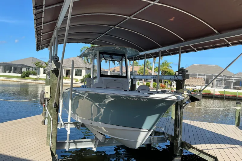 Slide: The Image of 2019 Sea Hunt Ultra 255 SE boat docked under a canopy in a scenic marina. - 7