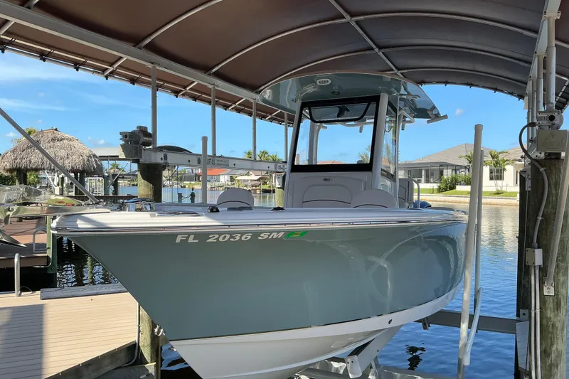 Slide: The Image of 2019 Sea Hunt Ultra 255 SE boat docked under a canopy in a marina. - 8